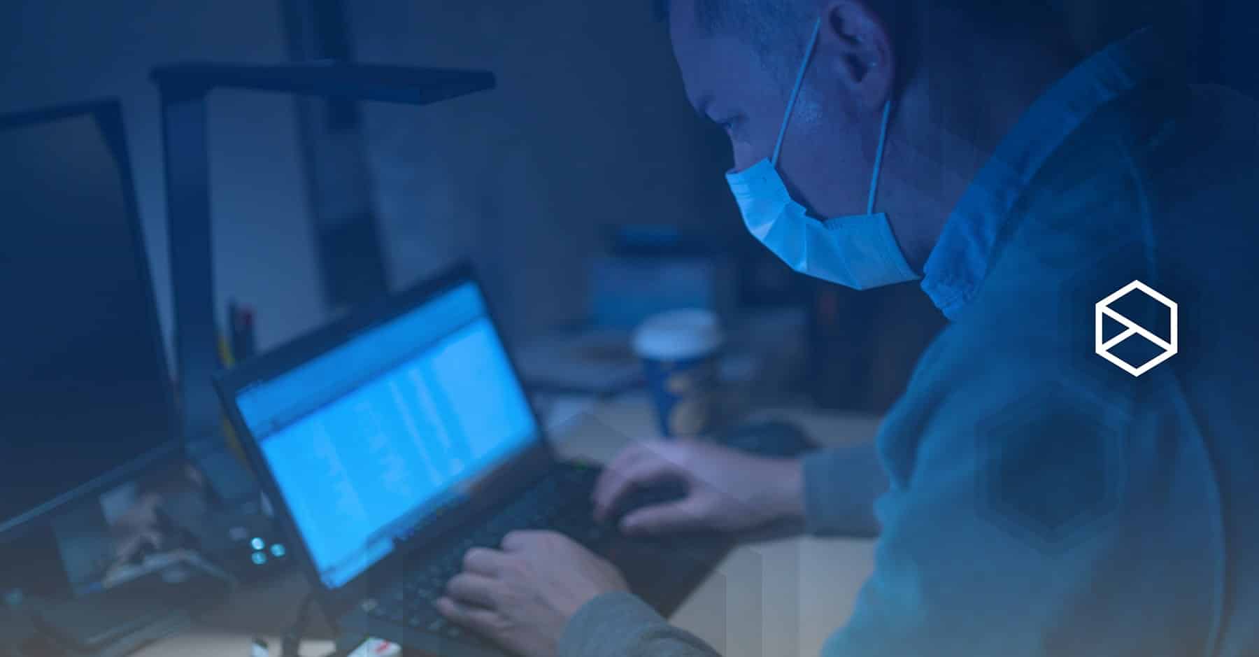 Man working on laptop while wearing surgical face mask